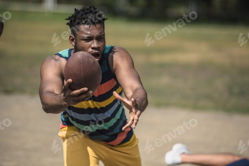 Preview: young handsome african american male football player with ball on court