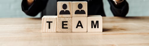Preview: panoramic shot of businesswoman near wooden cubes with human shapes and team letters