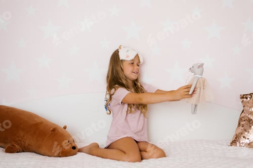 Preview: Girl is sitting on the bed and looking at her favorite stuffed toy