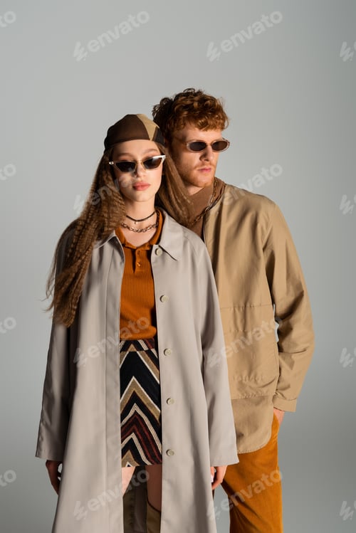 Preview: young and stylish couple in autumnal outfits posing isolated on grey