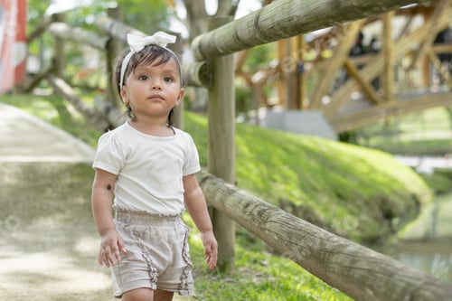 Preview: little brown-skinned latina girl, standing in the middle of the path looking curiously