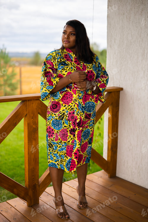 Preview: Beautiful african american woman enjoying evening on village and nature on terrace of country house