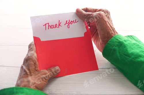 Preview: senior women's hand holding thank you letter , rear view