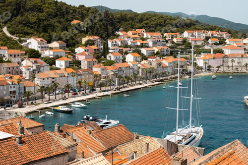 Preview: Aerial shot of a bay next to a townscape in the background of mountains.