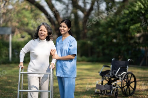 Vorschau: Die Pflegekraft hilft asiatischen Senioren oder älteren alten Damen, mit einem Gehstock im Garten spazieren zu gehen.