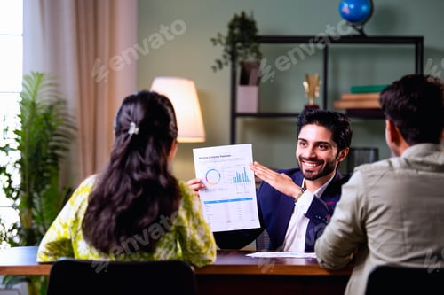 Preview: Young Indian husband and wife analyzing financial reports with planner in office