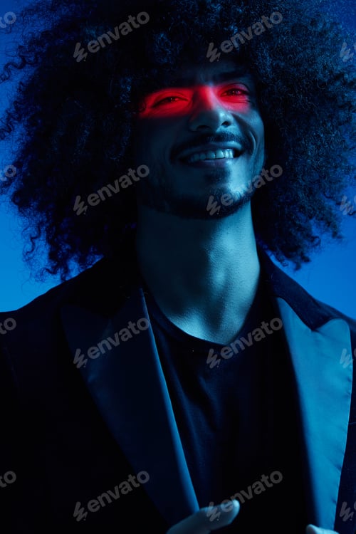 Preview: Fashion portrait of a man with curly hair on a blue background with a red stripe of light