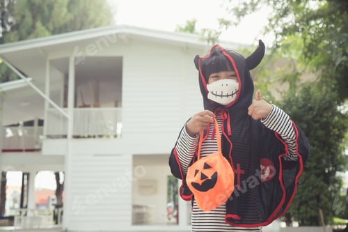 Preview: Asian little girl in a Halloween costume in a medical mask .