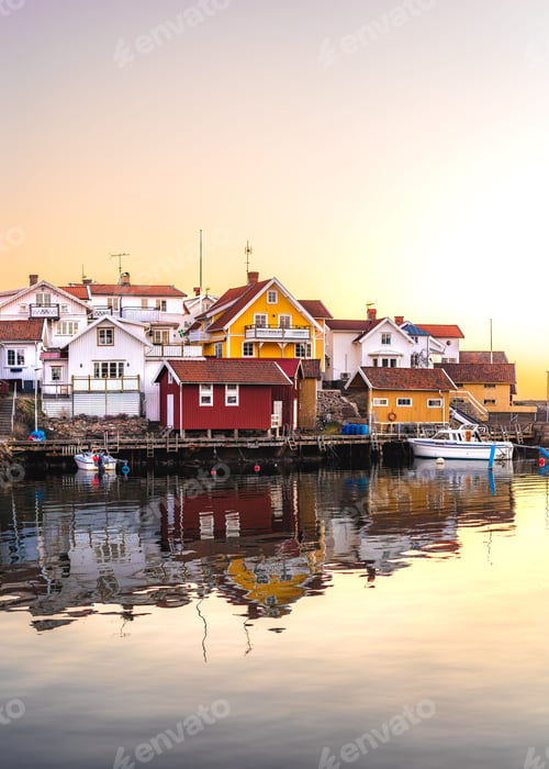 Preview: Vertical shot of a small houses of Lysekil on the lakeside and boats in water at sunset in Sweden