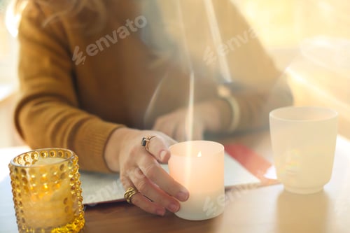 Preview: Blurred image of woman lightning scented candle while working remotely at home