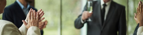 Preview: Middle Aged Caucasian Man Holding Champagne Glass Surrounded by Applauding Colleagues