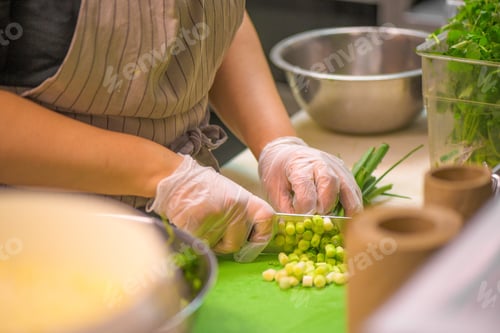 Preview: Selective focus shot of chef cutting green onions on a board