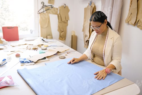 Preview: Designer works with blue fabric on cutting table