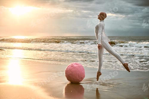 Preview: Hairless ballerina with alopecia in white futuristic suit jumps along seashore at sunset sea