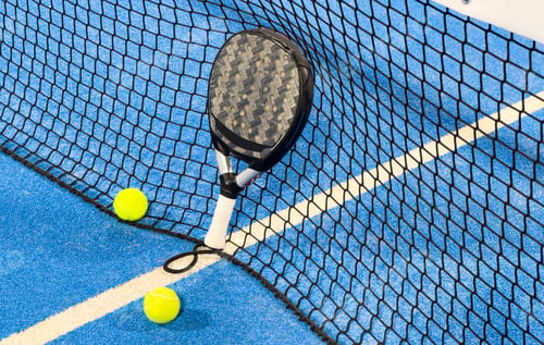 Preview: balls in the net on a blue paddle tennis court