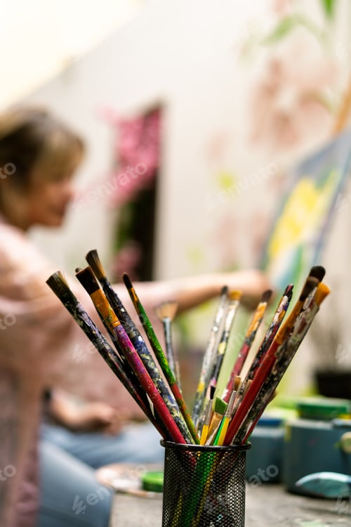 Preview: Paint brushes with artist working in background
