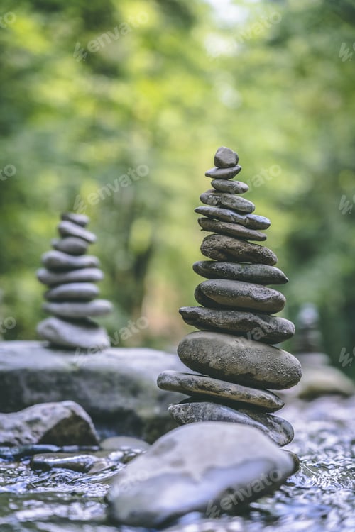 Preview: Vertical shot of two stone pyramids balanced on a river water