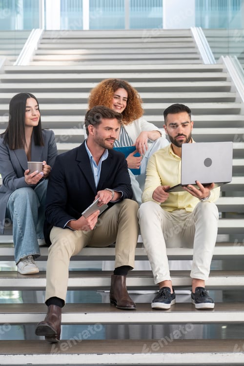 Preview: Business team collaborating on laptop and tablet on office stairs