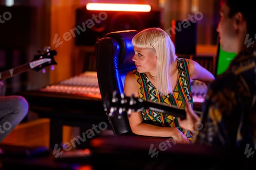 Preview: Female sound engineer at recording studio listening guitarists playing