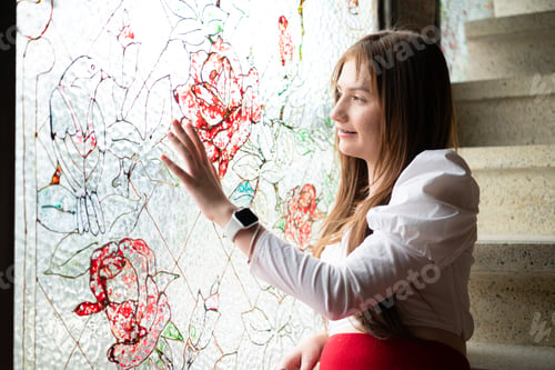 Preview: Portrait of Teenage girl looking through the window at a graffiti on the wall.