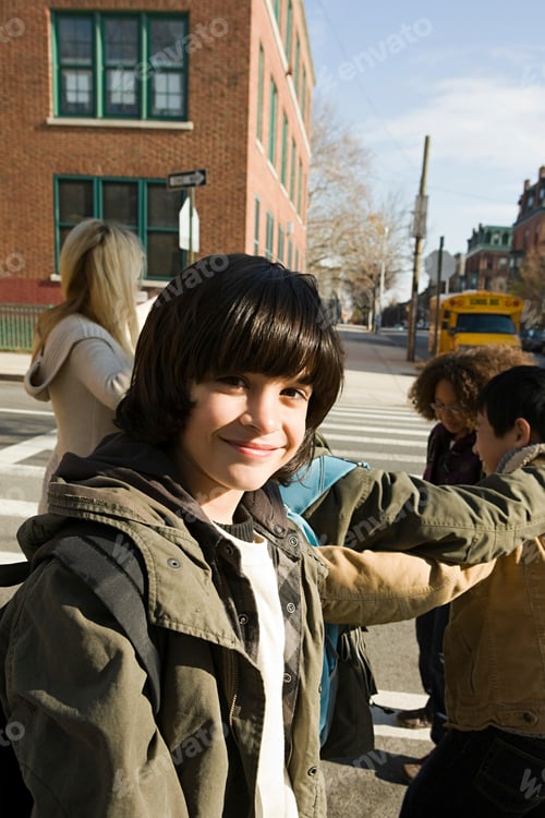 Preview: Young boy smiling on a sunny city street with friends in the background.
