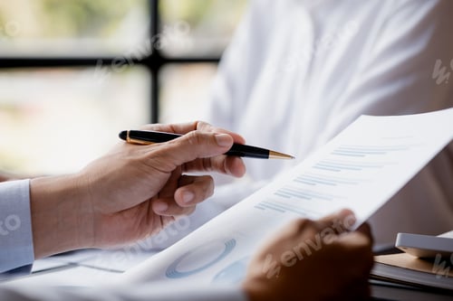 Preview: A close-up view of a businessman holding a pen pointing at a bar chart on a company financial.