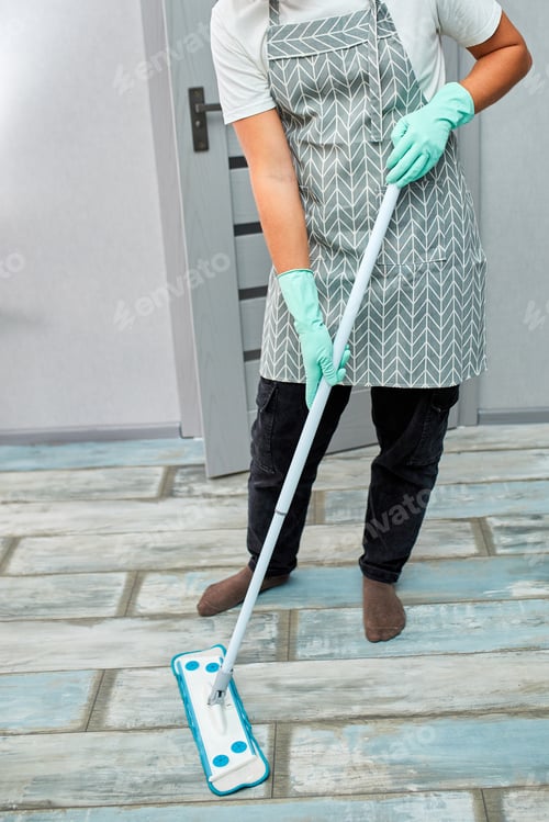 Preview: Bearded man in gloves with mop in hand cleaning floor in the house