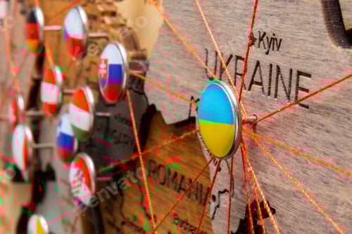 Preview: Ukraine flag on the pushpin and red threads on the wooden map connected with Europe