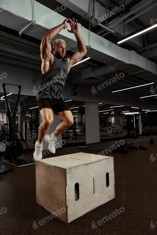 Preview: Sexy muscular men using the platform for his legs on a dark colorful background of gym.