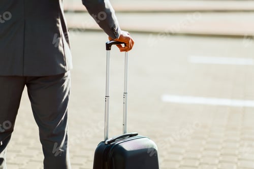 Preview: Unrecognizable businessman standing with luggage by airport