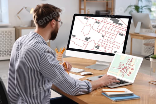 Preview: Man working with cadastral map on computers at table in office