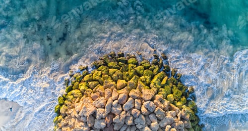 Preview: Aerial shot of rocks on each other surrounded by the wavy sea under the sunlight at daytime