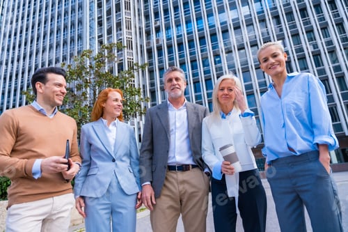 Preview: Group of confident business professionals posing in front of a modern building