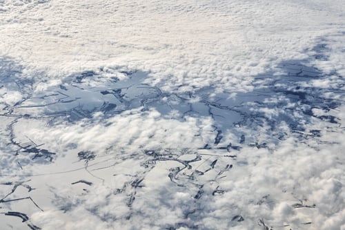 Preview: Aerial cloudscape view over clouds top to snow covered rivers, roads, cities and fields, winter air