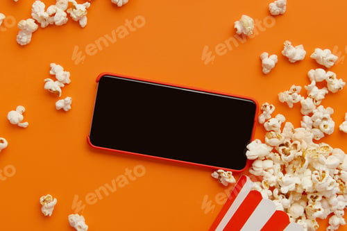 Preview: Smartphone and box of popcorn on an orange background