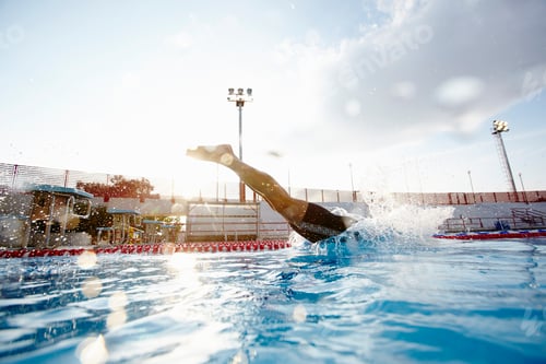 Preview: Swimmer diving into an outdoor swimming pool with a dynamic splash, under a clear sky.