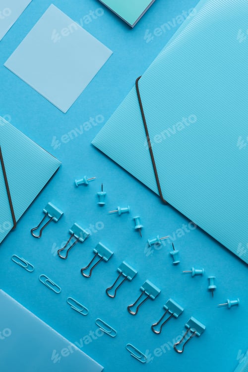 Preview: top view of paper folders and various stationery isolated on blue