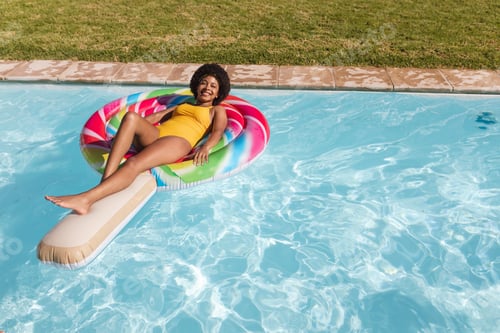 Preview: Mixed race woman having fun playing on inflatable in swimming pool