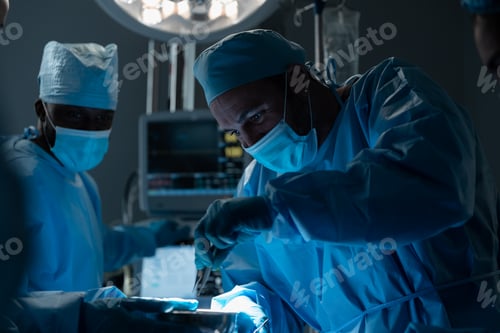 Preview: Caucasian male surgeon wearing face mask and protective clothing during operation in hospital