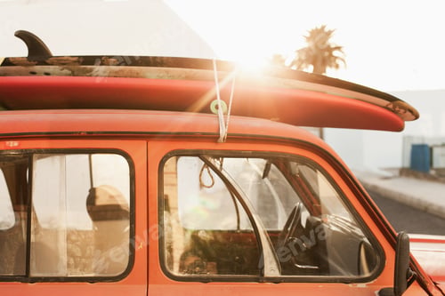 Preview: A stack of surfboards on a retro car roof with sun shining. Summer and surf background wallpaper.