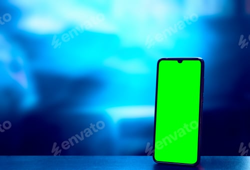 Preview: Closeup shot of a green screen on a mobile phone against a blue blurry background