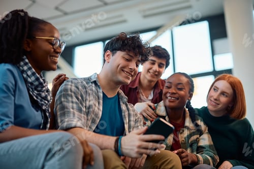 Preview: Multiracial group of happy students using cell phone in lecture hall.