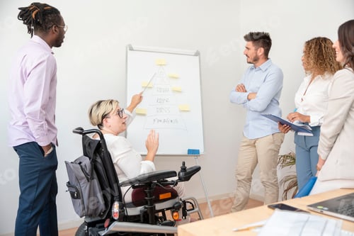 Preview: a woman in a wheelchair with disability pointing at presentation on whiteboard