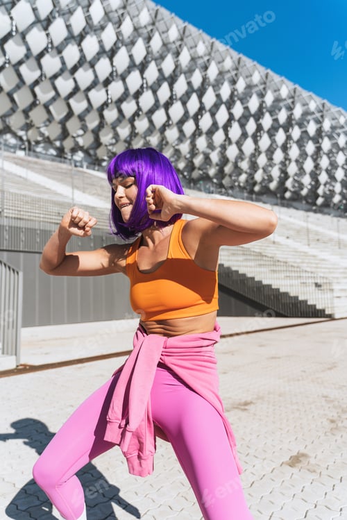 Preview: Carefree active woman dancer wearing colorful sportswear having fun on the street