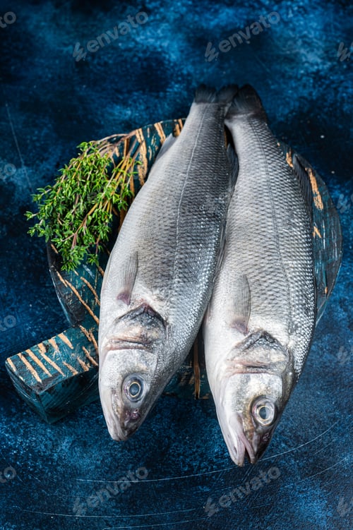 Preview: Uncooked Raw Sea Bass fish, Seabass with thyme. Blue background. Top view