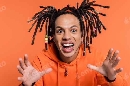Preview: excited multiracial man with dreadlocks gesturing on coral background