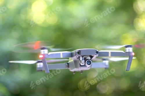Preview: Drone aircraft with blurred fast rotating propellers and video camera flying in air.