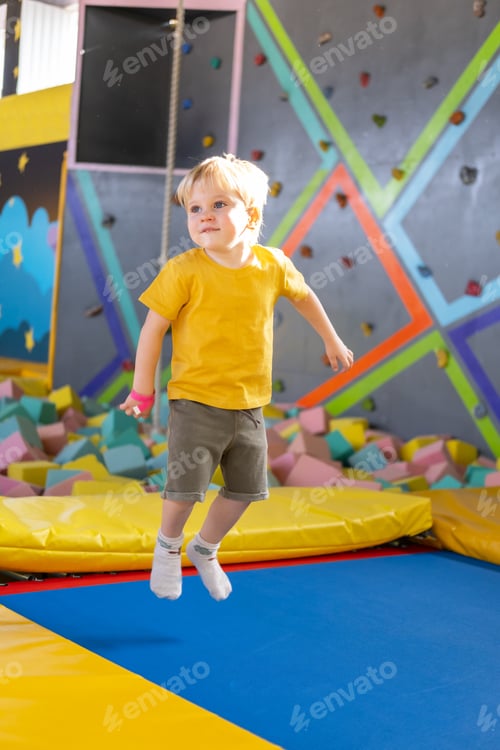 Preview: cute blond little boy jumps in a trampoline park, children activity
