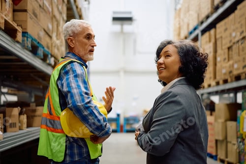 Preview: Happy businesswoman and warehouse foreman communicating at storage compartment.