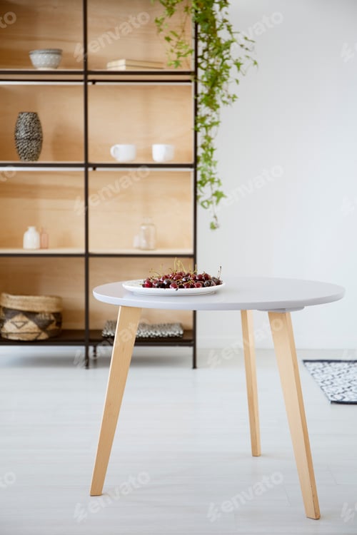 Preview: Real photo of a plate of cherries on a round, wooden table in br